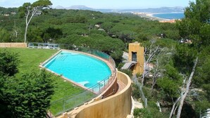 Une piscine entourée d’une végétation luxuriante, avec vue sur la côte.