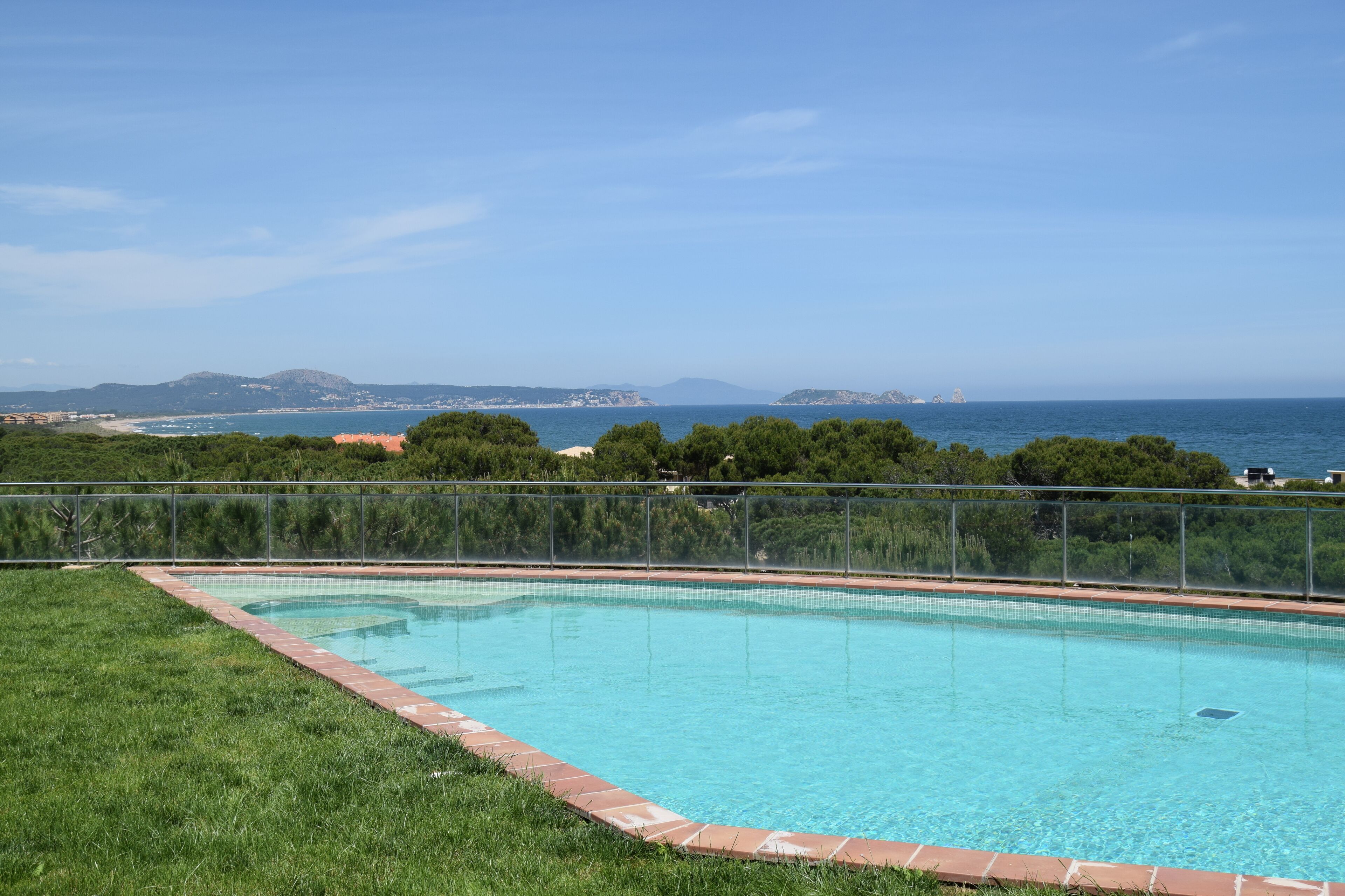 A swimming pool with a clear view of the sea and distant mountains.