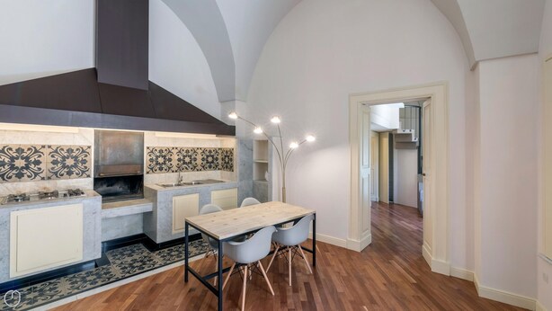 A modern kitchen with a central island, a built-in oven, and a dining area with a table and chairs. - Palazzo Acquaviva - Il Forno Antico (Lecce)