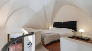 A bedroom with a bed, bedside tables, and a staircase. - Palazzo Acquaviva - Il Forno Antico (Lecce)