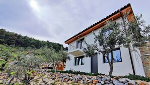 A modern two-story house with a stone foundation and a wooden roof. - Small Villa Bella (Sporades)