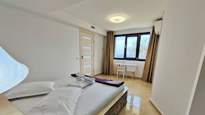 A hotel room with a bed, a desk, a chair, and a window with curtains. - Small Villa Bella (Sporades)