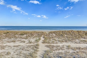 Enjoy serene ocean views from the beach, surrounded by grassy dunes and a tranquil path leading to the calm waters.