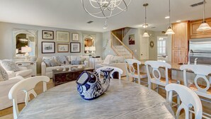 A spacious living room with a marble table, white furniture, and a chandelier. - Gorgeous 2nd Floor Sailmaker Villa | Private Patio Overlooking Pool | Purchasable Summer Beach Club Access (Fernandina Beach)
