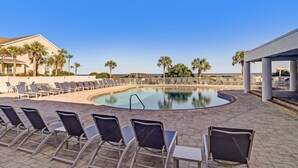 A pool area with lounge chairs, a pool, and palm trees. - Gorgeous 2nd Floor Sailmaker Villa | Private Patio Overlooking Pool | Purchasable Summer Beach Club Access (Fernandina Beach)