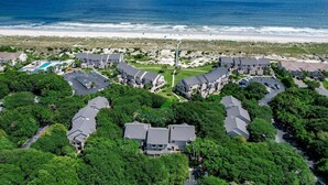 An aerial view of a coastal residential area with houses, a beach, and a clear sky. - Gorgeous 2nd Floor Sailmaker Villa | Private Patio Overlooking Pool | Purchasable Summer Beach Club Access (Fernandina Beach)