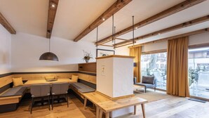 A modern interior with a wooden bench seating area, a central table, and a large window offering a view of the outside. - mit 2 Schlafzimmern by Interhome (Kitzbühel)