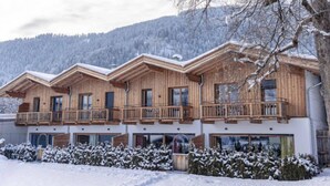 A wooden chalet with multiple balconies, large windows, and a snowy landscape in the background. - mit 2 Schlafzimmern by Interhome (Kitzbühel)