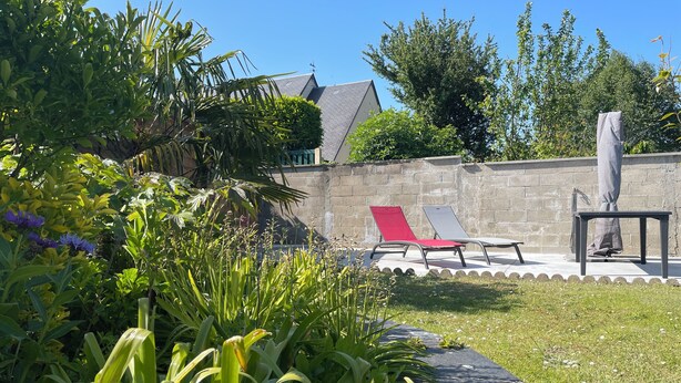 A garden area with a stone wall, two lounge chairs, and a table with an umbrella. - La Renaissance *** - Collection La 21ème Planche (Bayeux)