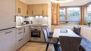 Una cucina moderna con mobili in legno, forno integrato e zona pranzo con una panca e sedie.