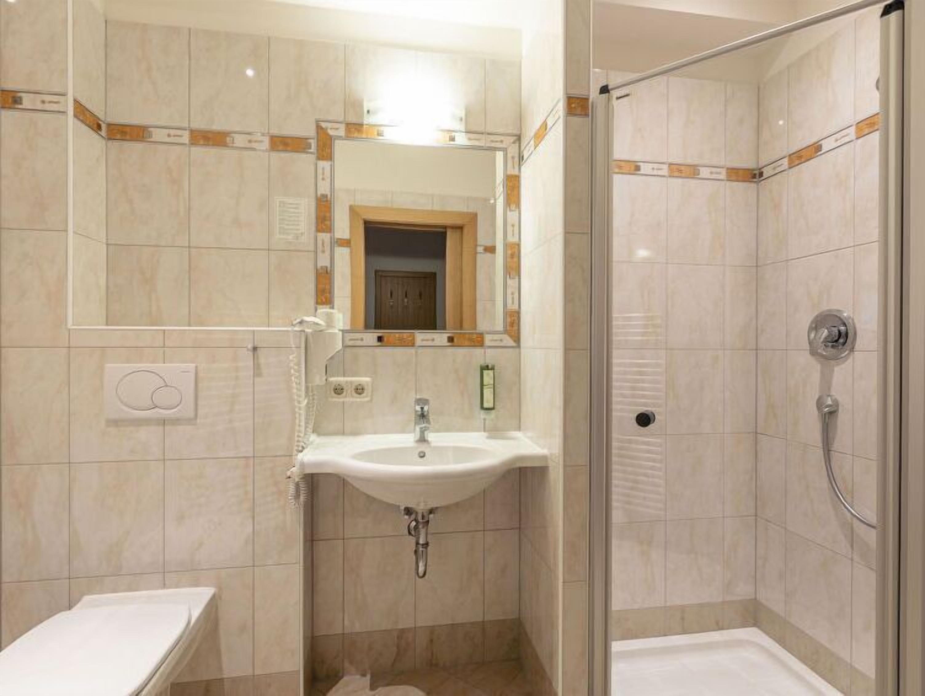 A bathroom with a sink, mirror, and shower.