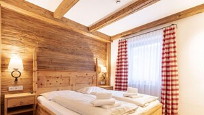 Ein Schlafzimmer aus Holz mit einem Bett, zwei Nachttischen und einem Fenster mit roten und weißen Karottenvorhängen.