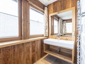 A bathroom with wooden walls, a white sink, and a large mirror.