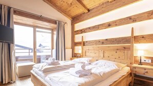 Une chambre à coucher avec un cadre en bois, un grand lit, des lampes de chevet et une fenêtre avec des rideaux.