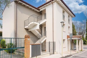 A two-story building with a central staircase, a gated entrance, and a small covered area.
