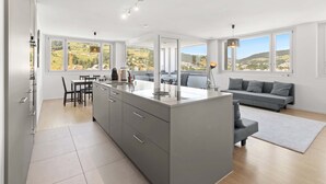 A modern kitchen with a central island, dining area, and a sofa.