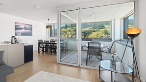 A modern living room with a sliding glass door leading to a balcony with a scenic view.