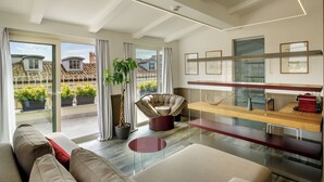 Una sala de estar moderna con un sofá, una mesa de centro de vidrio, una planta en maceta y vistas al balcón exterior.