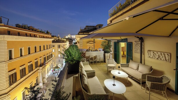 Una terraza en la azotea con mobiliario exterior, una zona de bar y vistas a la ciudad.