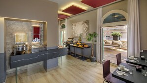 Un moderno vestíbulo de hotel con recepción de mármol, zona de buffet y asientos con vistas al área exterior.