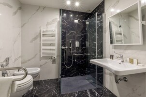 Et moderne badeværelse med en brusekabine med glasdøre, en hvid vask og et toilet.