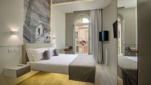 Habitación de hotel moderna con una cama grande, un televisor de pantalla plana, una mesita de noche y vistas a la ciudad a través de un ventanal de arco.