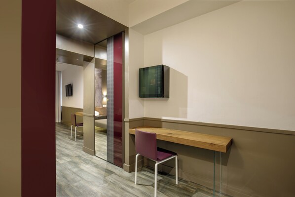 A modern office space with a wooden desk, a purple chair, and a glass partition.