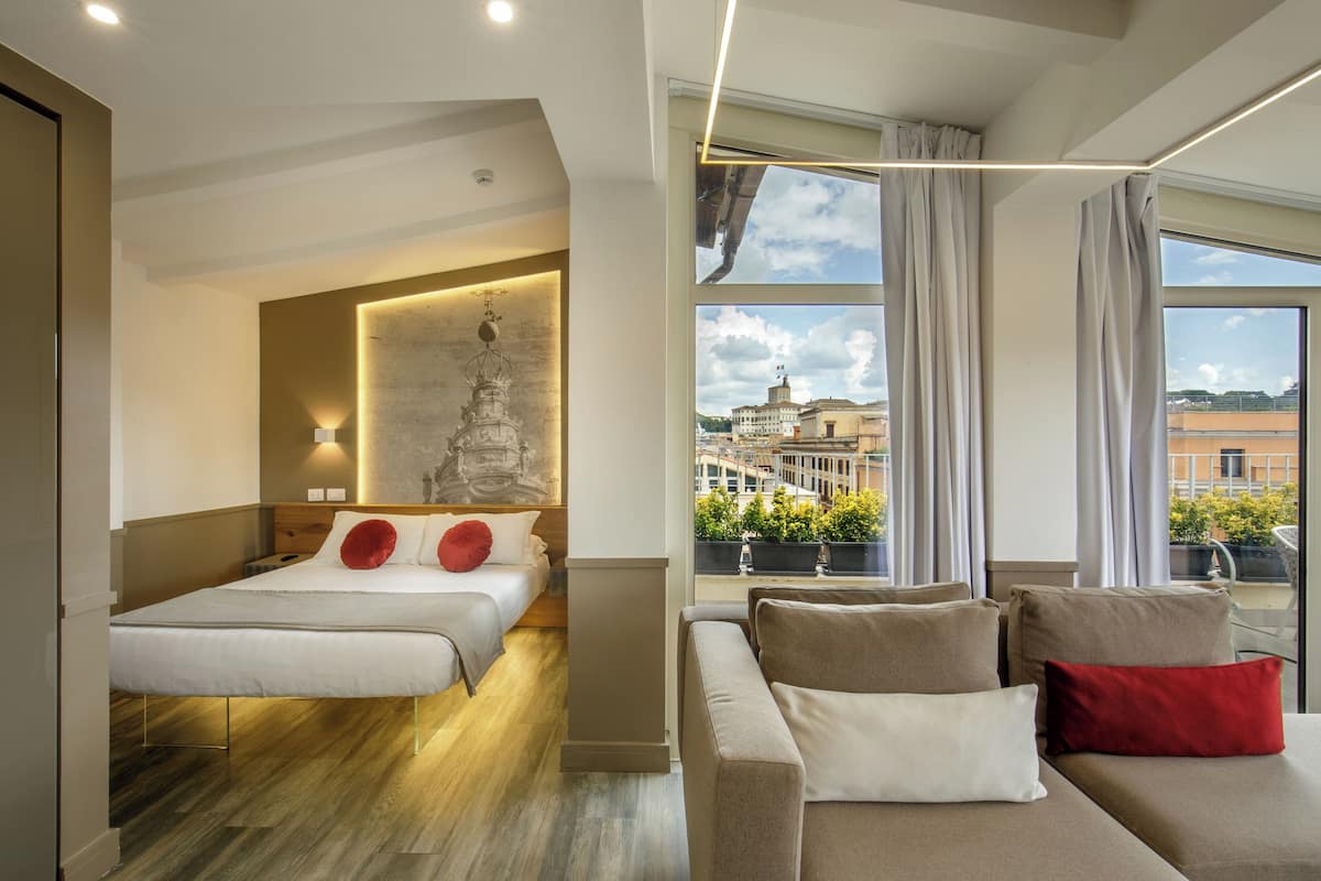 Moderni hotellihuone, jossa on suuri sänky, sohva ja näkymä kaupunkiin.