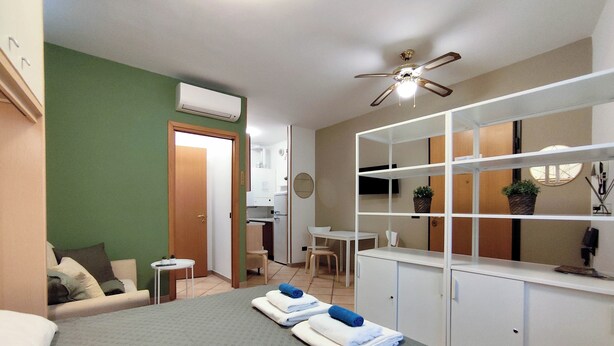 Une chambre d’hôtel comprenant un lit, un bureau, une chaise, une petite kitchenette et une salle de bain.