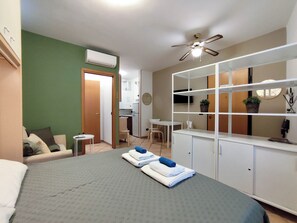 Een hotelkamer met een bed, een bureau, een stoel, een kitchenette en een badkamer.