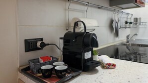 Une cuisine équipée d’une machine à café, d’un plateau avec des tasses et d’un panier contenant des sachets de thé.