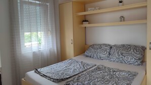 Une chambre à coucher avec un lit, des coussins à motifs, une table de chevet et une fenêtre avec des rideaux.