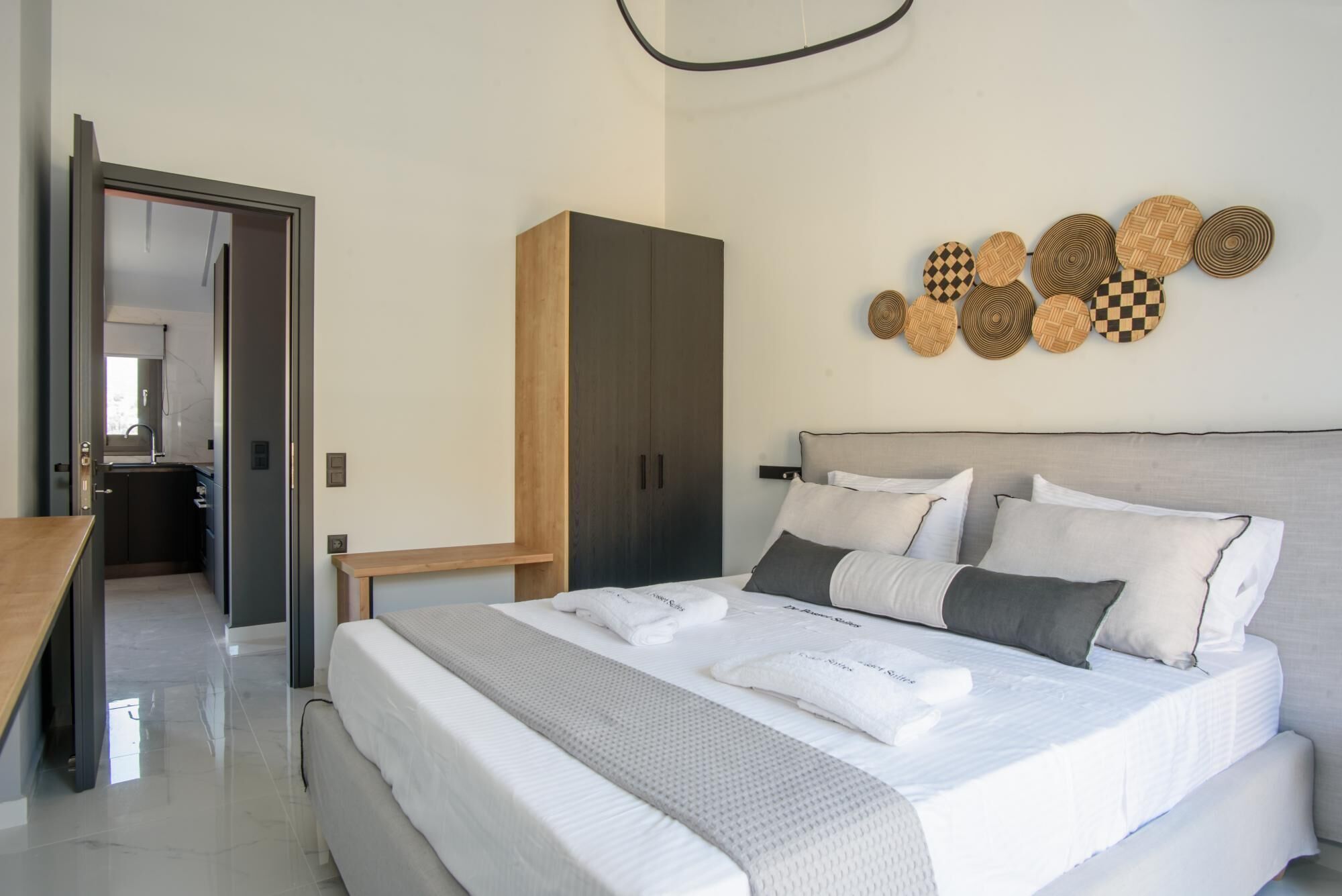A modern bedroom with a large bed, a wardrobe, and a wall-mounted circular decoration.