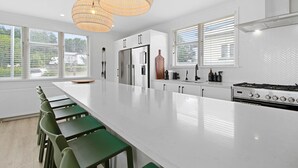 Une cuisine moderne dotée d’un grand îlot central, d’appareils électroménagers en acier inoxydable et de tabourets de bar verts.