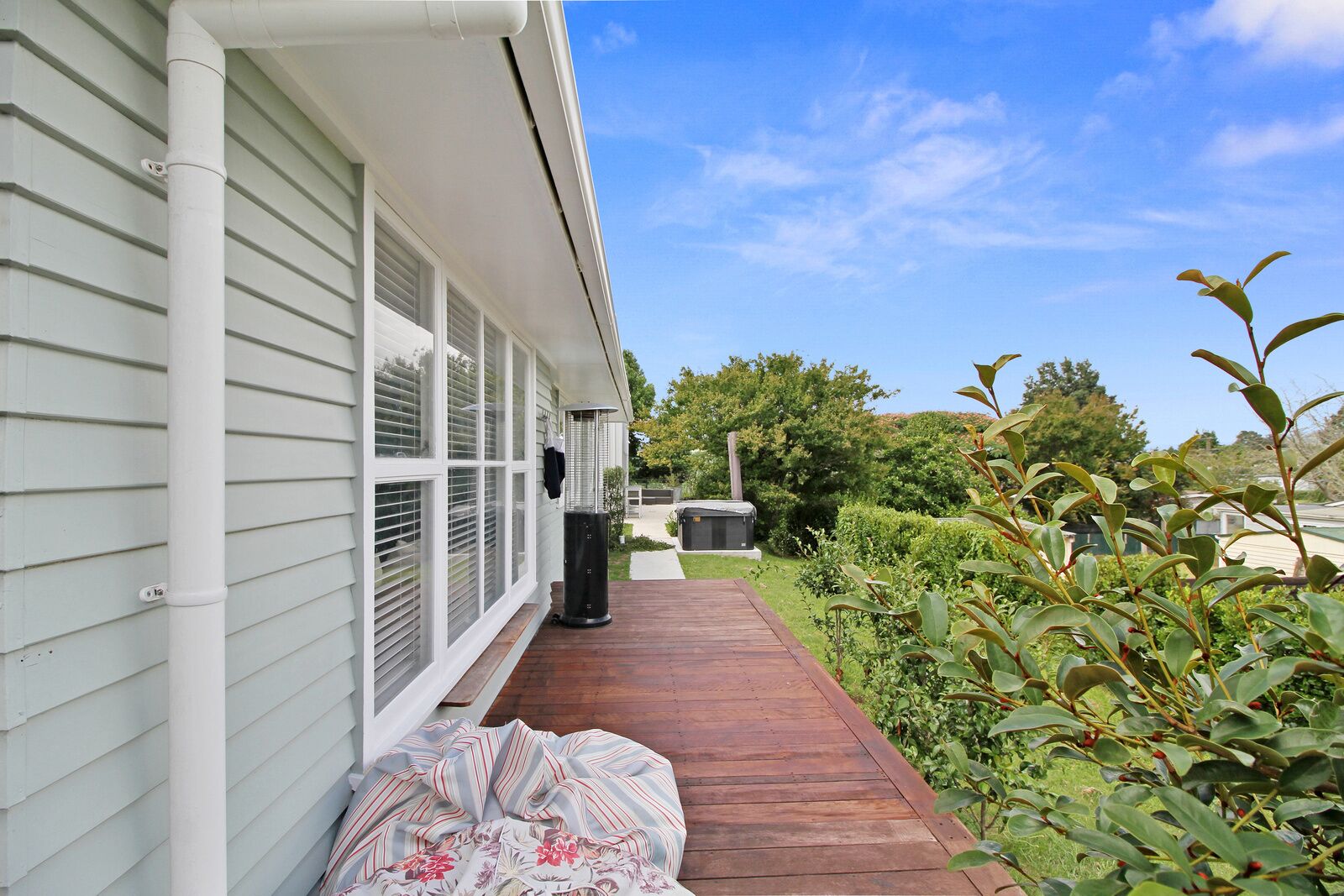 A wooden deck leading to a house with white siding and large windows.