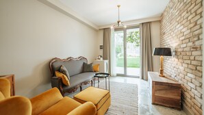 A modern living room with a sofa, ottoman, and a small table. There is a brick wall and a ceiling fan. - oDam Otel (Urla)
