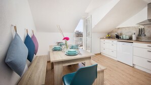 Een moderne keuken met witte kasten, een houten eettafel en blauwgroene stoelen.