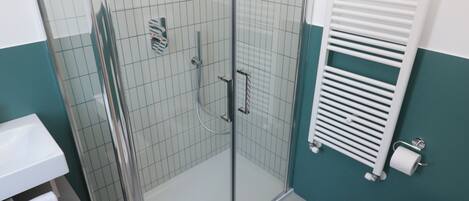 A modern bathroom with a glass-enclosed shower, a white sink, and a bidet.