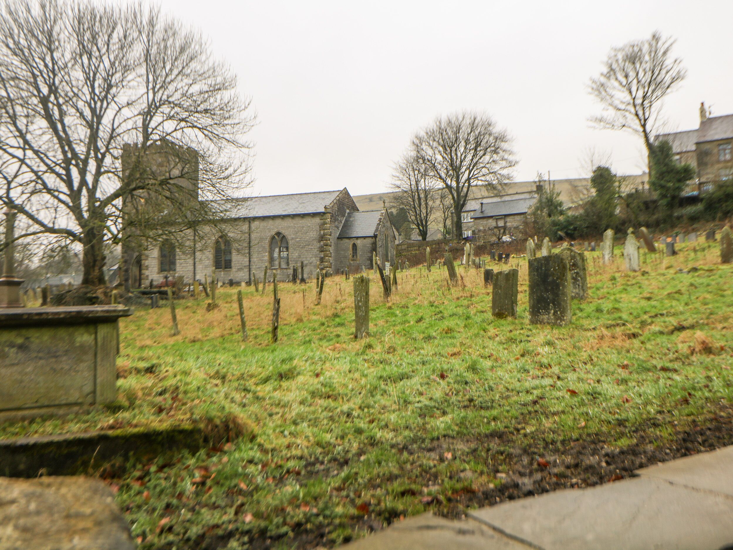 A cemetery with stone headstones and a church in the background.