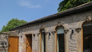 A stone building with multiple arched windows and a wooden door.