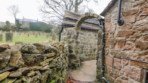 A stone structure with a wooden bench and a metal pipe.