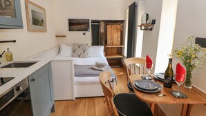 A compact bedroom with a bed, bedside table, and a small window.
