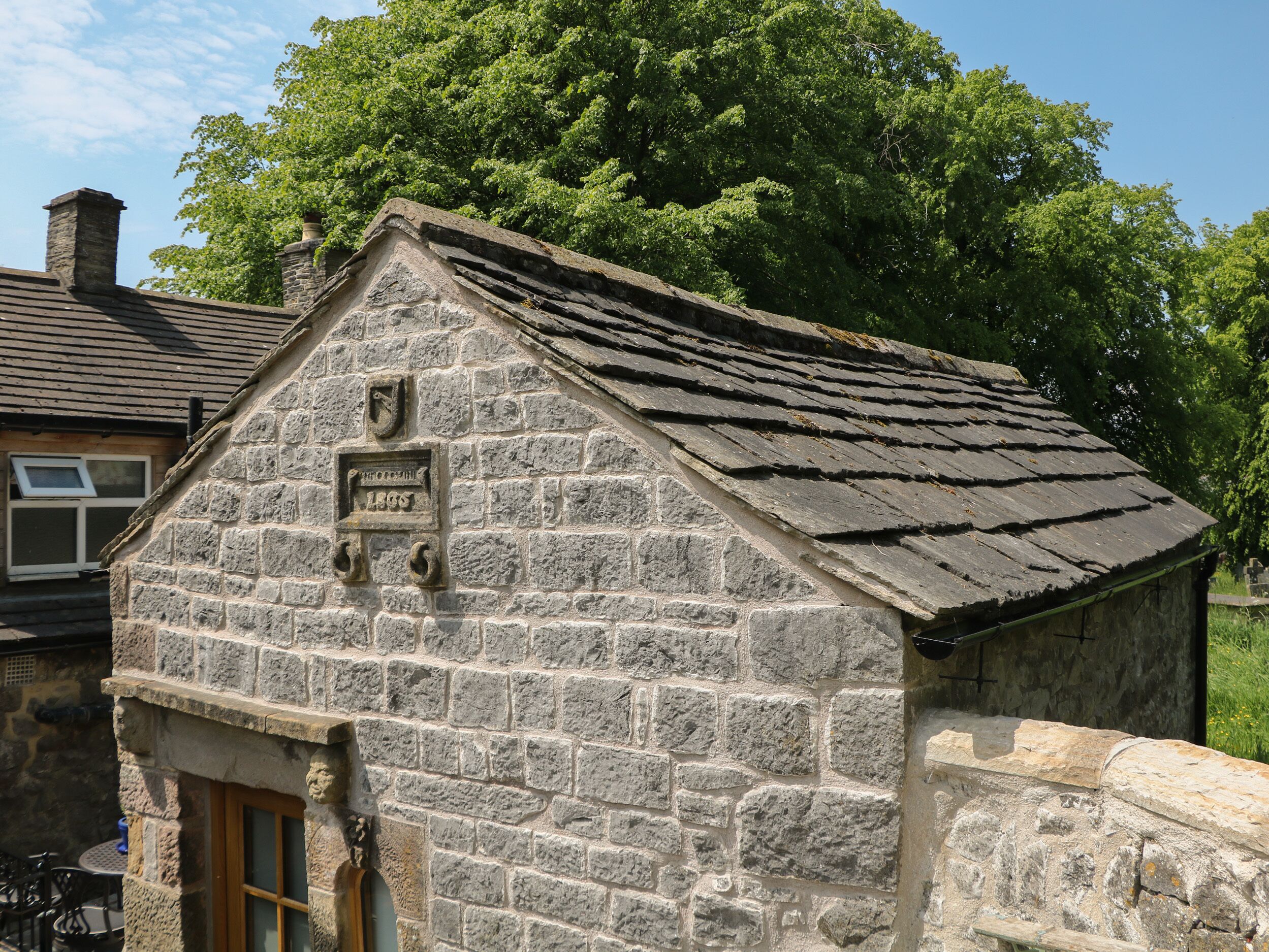 A stone building with a sloped roof and a wooden door.