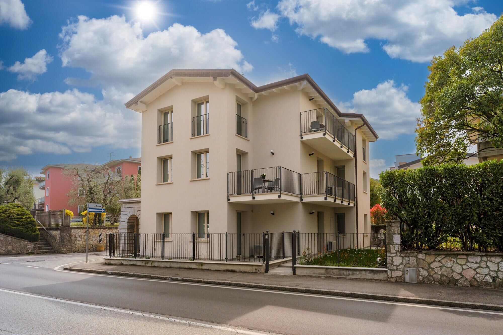 A multi-story residential building with balconies, a stone facade, and a clear sky.