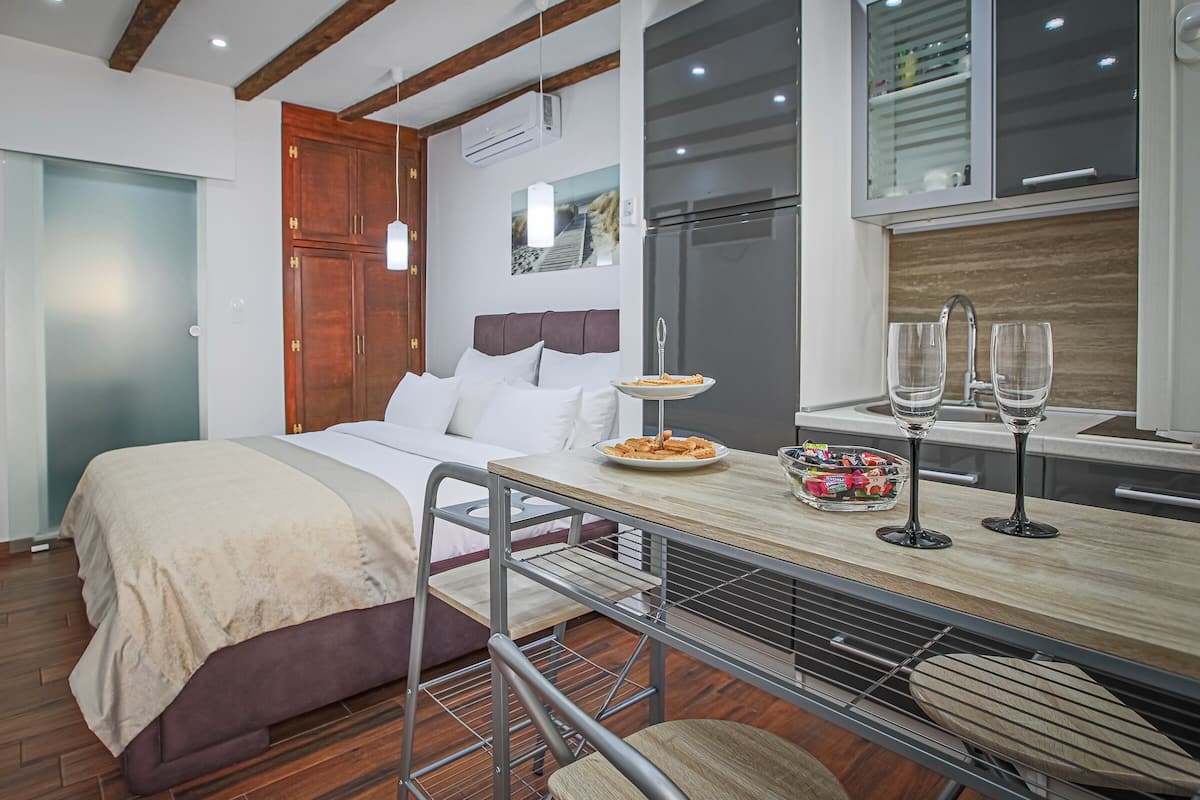 A compact room with a bed, kitchenette, and a dining area.