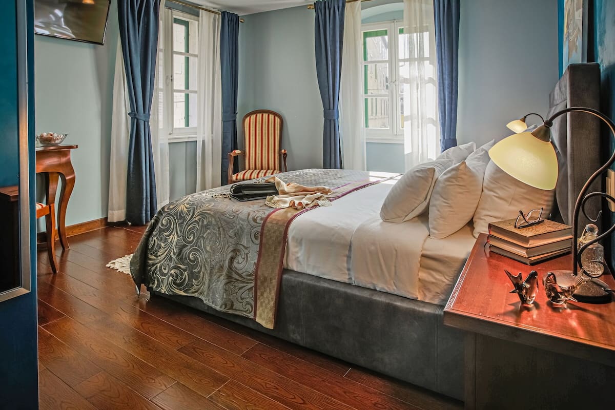 A neatly arranged bedroom with a large bed, bedside table, and a chair.