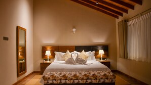 Une chambre à coucher bien aménagée, avec un grand lit, deux tables de chevet avec des lampes, un miroir et un plafond en bois.