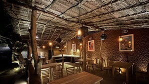 Un intérieur caractérisé par un plafond en chaume, des tables et des chaises en bois, et des murs ornés de tableaux encadrés.