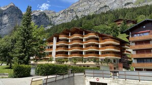 Un hotel a più piani con balconi, con le montagne sullo sfondo.