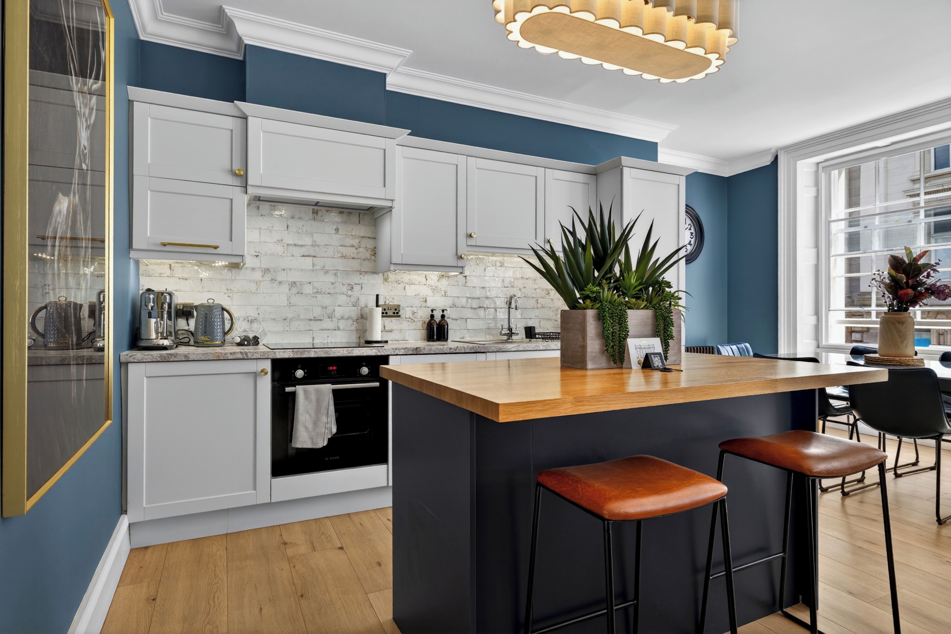 A modern kitchen with white cabinets, a wooden island, and bar stools.